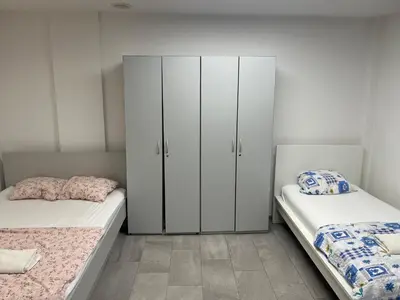 two beds in a room with white cabinets at New Modern App in Ljubljana