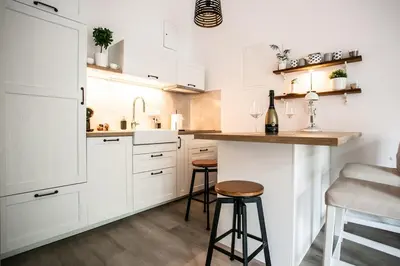 a kitchen with white cabinets and a counter and stools at Urska's adorable place in Ljubljana