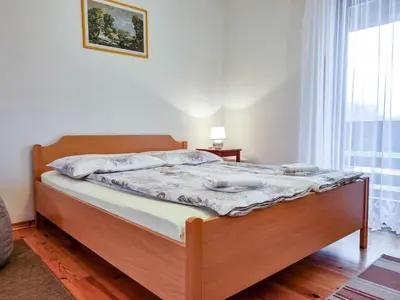 a bed with a wooden frame in a room with a window at Apartmaji Čok in Bovec
