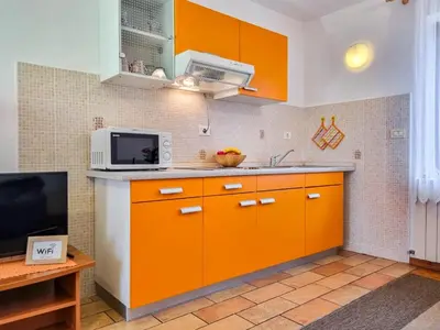 a kitchen with orange cabinets and a microwave at Apartmaji Čok in Bovec