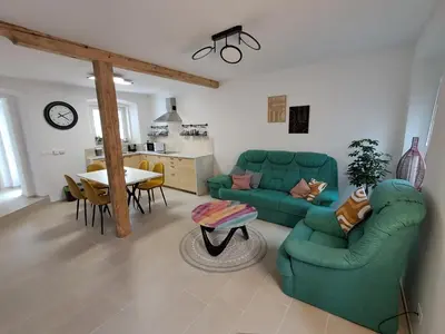 a living room with a green couch and a table at Rozalija house - Počitniška hiša z vrtom ob reki Soči v Solkanu in Solkan