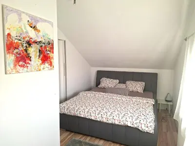 a bedroom with a bed and a painting on the wall at Holiday house Zala in Puconci