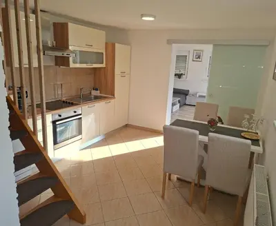 a kitchen and living room with a table and chairs at Holiday house Zala in Puconci