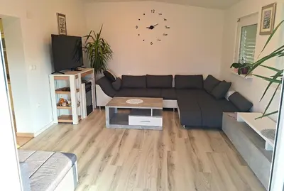 a living room with a couch and a clock on the wall at Holiday house Zala in Puconci