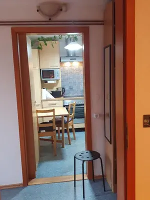 a kitchen and dining room with a table and a stool at ALPINE VILLAGE APARTMENT with a private terrace, garden, and parking - at a walking distance from LAKE BLED in Bohinjska Bela
