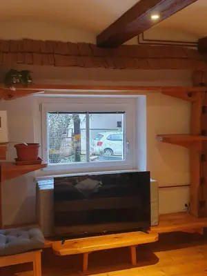 a living room with a tv and a window at ALPINE VILLAGE APARTMENT with a private terrace, garden, and parking - at a walking distance from LAKE BLED in Bohinjska Bela
