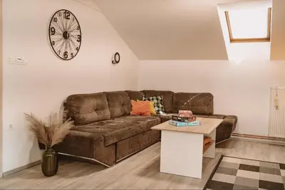 a living room with a couch and a clock on the wall at Green Hill in Jesenice na Dolenjskem