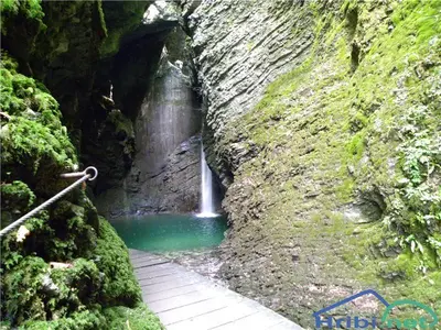 a waterfall in a cave with a pathway in front of it at Apartma Magdalena in Kobarid