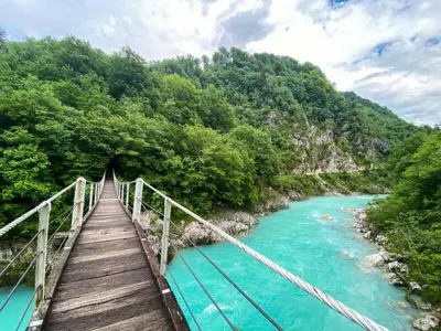 a wooden bridge over a river with blue water at Apartma Magdalena in Kobarid