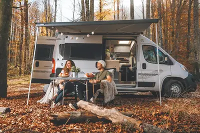 two people sitting at a table in front of an rv at Robeta Ares in Šenčur