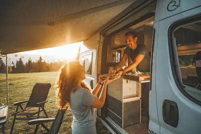a man and woman preparing food in an rv at Robeta Ares in Šenčur