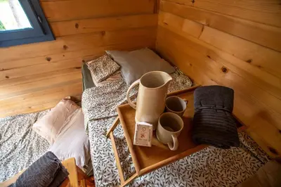 a bed with a tray with two cups on it at mobile house on a herbs farm in Ajdovščina
