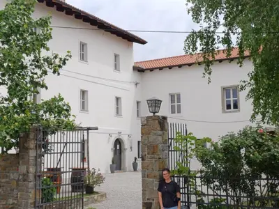 a woman standing in front of a fence in front of a white house at Grad Kojsko in Kojsko