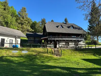 a large house with a gambrel roof on a lawn at Planinska koča na Kopitniku in Dol pri Hrastniku