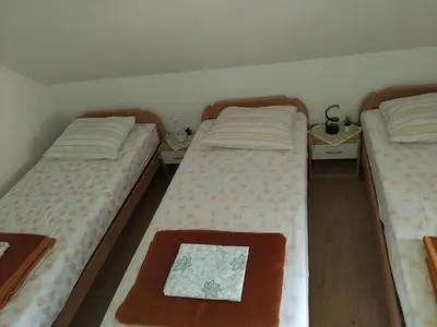 two twin beds in a room with two tables at Planinska koča na Kopitniku in Dol pri Hrastniku