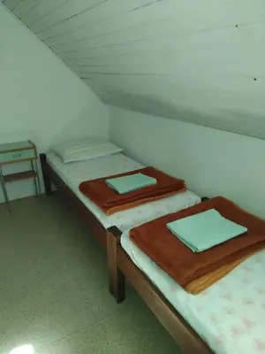 two twin beds in a room with a table at Planinska koča na Kopitniku in Dol pri Hrastniku