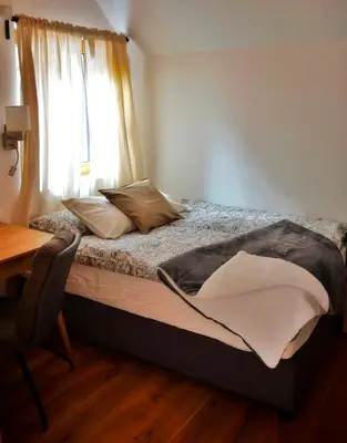 a bed in a room with a window and a desk at Hiša Plesnik in Solčava