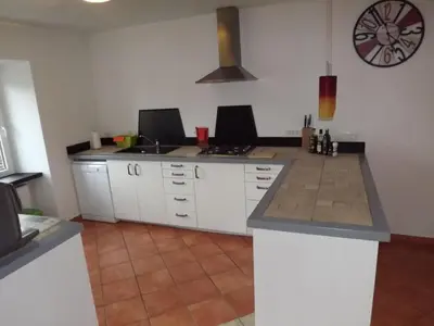 a kitchen with white cabinets and a clock on the wall at Velika Hiša in Rašica
