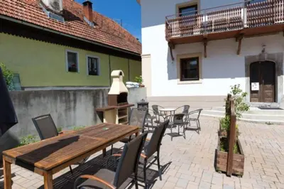 a patio with a wooden table and chairs and a building at Velika Hiša in Rašica