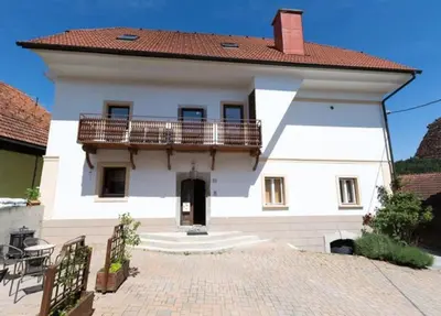 a white house with a balcony and a patio at Velika Hiša in Rašica