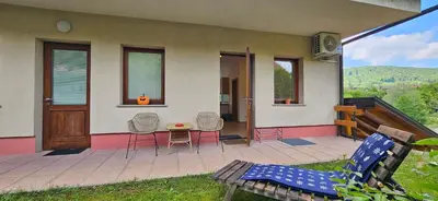 a house with chairs and a table on a patio at Apartments Dvor by the Krka river in Rove