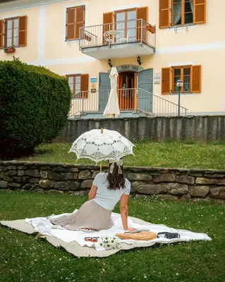 a woman sitting on a blanket with an umbrella at Dvorec Jeruzalem in Ivanjkovci