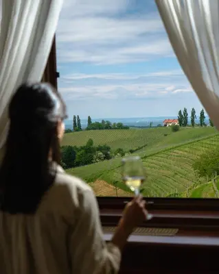 a woman looking out of a window at a vineyard at Dvorec Jeruzalem in Ivanjkovci