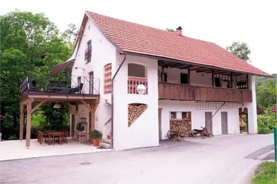 a large white building with a balcony and a table at Apartment Tlaka in Gornji Grad