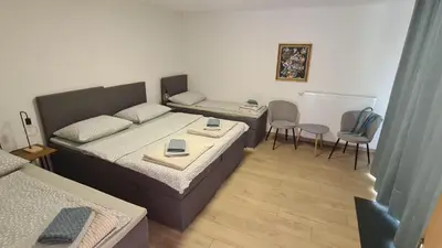 a small room with two beds and a table and chairs at Brne Family House in Postojna