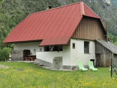 a house with two chairs and a red roof at Idina domačija in Trenta