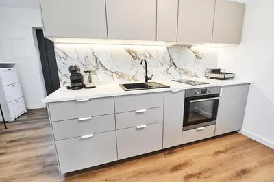 a white kitchen with white cabinets and a sink at Blue Alpine Nest in Komenda