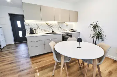 a white kitchen with a white table and chairs at Blue Alpine Nest in Komenda