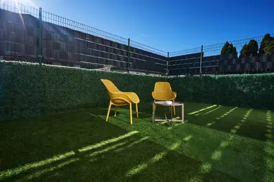 two yellow chairs sitting on the grass in front of a fence at Blue Alpine Nest in Komenda