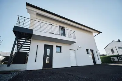 a white house with a staircase and a balcony at Blue Alpine Nest in Komenda