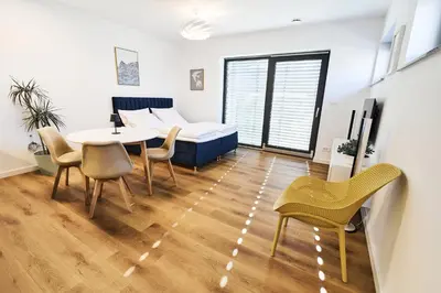 a living room with a table and chairs and a bed at Blue Alpine Nest in Komenda