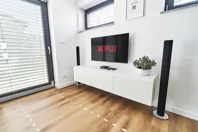 a living room with a tv on a white wall at Blue Alpine Nest in Komenda