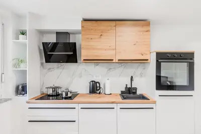 a kitchen with white cabinets and black appliances at Apartment SočaFly in Tolmin