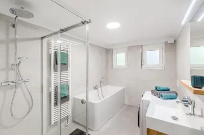 a white bathroom with a shower and a sink at Apartment SočaFly in Tolmin