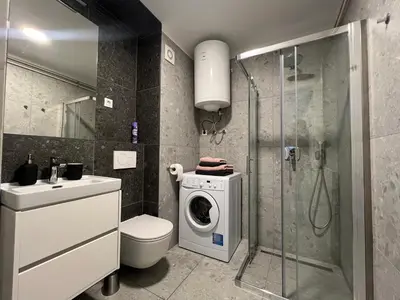 a bathroom with a washing machine and a toilet at Tabor in Ljubljana