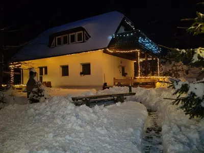 a house is covered in snow at night at apartma Pohorc - Kostanj in Pohorje