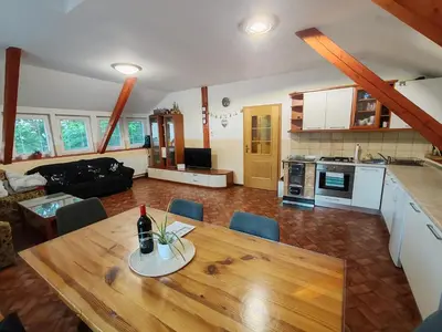 a living room with a wooden table and a kitchen at apartma Pohorc - Kostanj in Pohorje