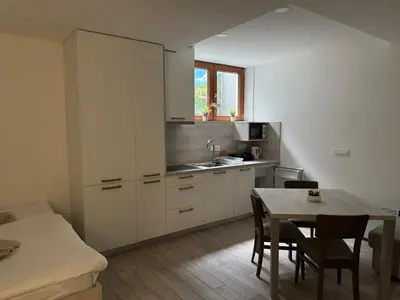 a kitchen with white cabinets and a table with chairs at U Izi 2 in Kranjska Gora