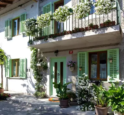 a building with green shutters and potted plants on it at Hiša pri poetu in Šempeter pri Gorici