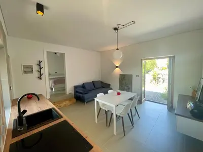 a living room with a white table and a blue couch at Studio Vila Olga in Dutovlje