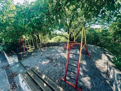 a playground with a swing set under a tree at Studio Vila Olga in Dutovlje