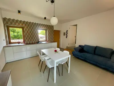 a living room with a white table and a blue couch at Studio Vila Olga in Dutovlje