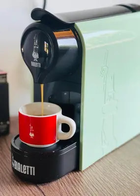 a coffee maker is pouring coffee into a red cup at Studio Vila Olga in Dutovlje