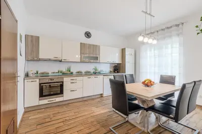 a kitchen with white cabinets and a wooden table and chairs at Apartment Stella with Two Bedrooms & Free Parking Spot in Bovec