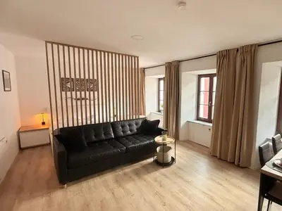 a living room with a black couch in a room at Apartments KrAnJ - City Studio Katka in Kranj