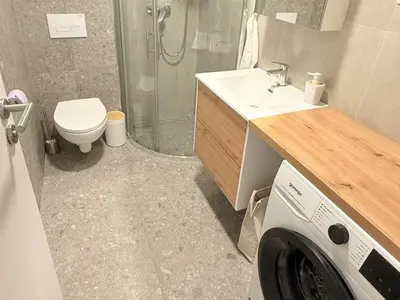 a bathroom with a sink and a washing machine at Apartments KrAnJ - City Studio Katka in Kranj